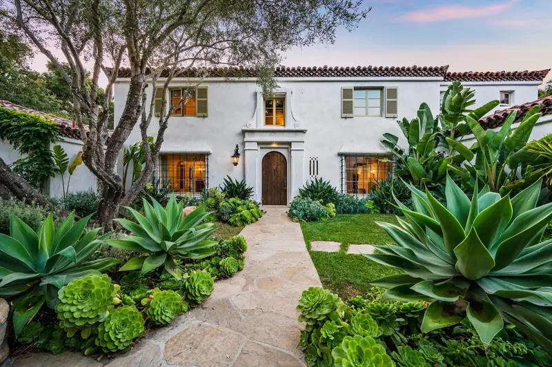Spanish-style home with agave succulent landscaping and stone path.