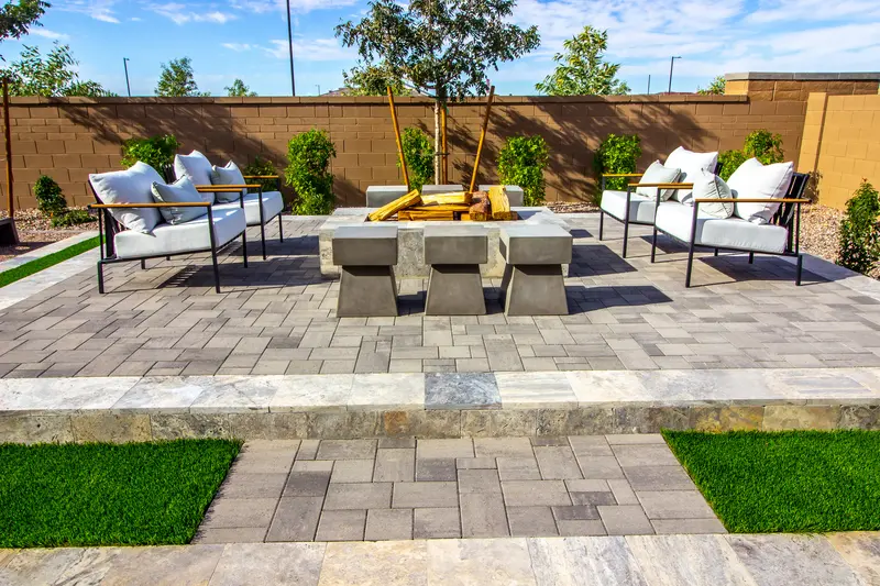 Custom paver patio featuring a central fire pit and modern seating.