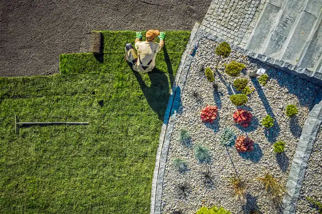 Laying fresh grass turf sod next to a pebble garden bed Laying fresh grass turf sod next to a pebble garden bed