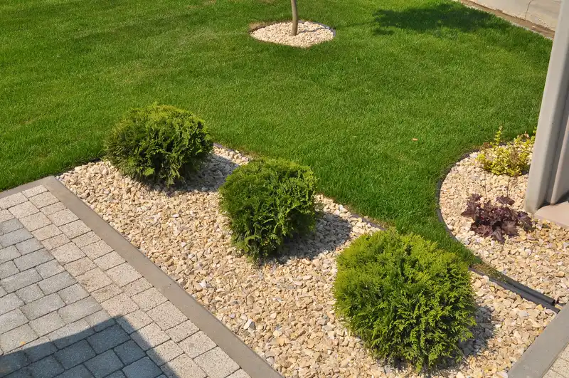 Landscape edging with white pebbles, round evergreen shrubs and lawn. Landscape edging with white pebbles, round evergreen shrubs and lawn.