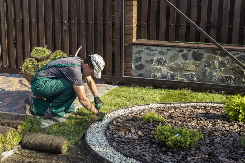 Landscaper installing new sod grass next to a gravel garden border. Landscaper installing new sod grass next to a gravel garden border.
